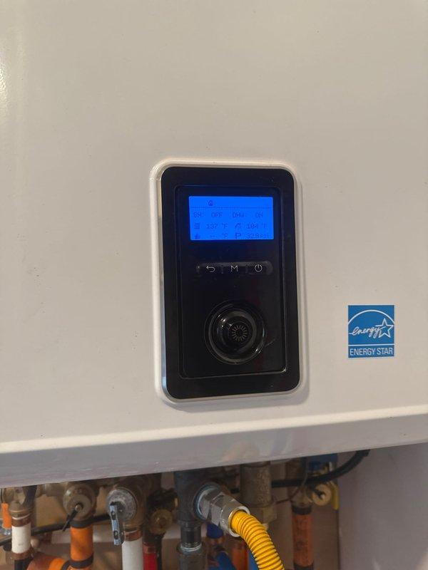 Performed a complete flush of the boiler system to remove sediment and contaminants, evidenced by the greenish discharge collected in the containment bucket. Inspected the wall-mounted unit with digital controls and Energy Star certification, verifying proper operation and temperature readings after service completion.