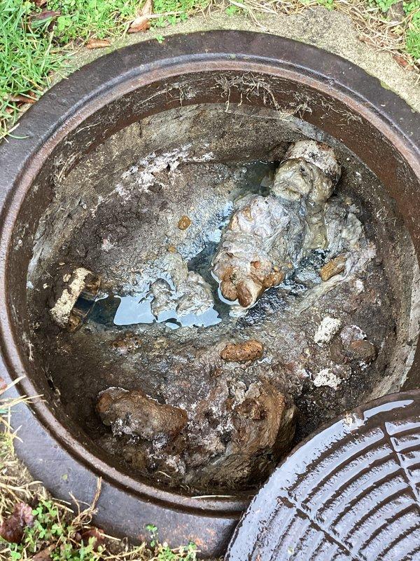 Conducted camera inspection of drain system at unit B to investigate suspected clogged line. Found catch basin heavily obstructed with mud, sediment, and debris, preventing proper drainage. Documented condition of exterior drainage access point for follow-up regarding previously identified manhole issue.