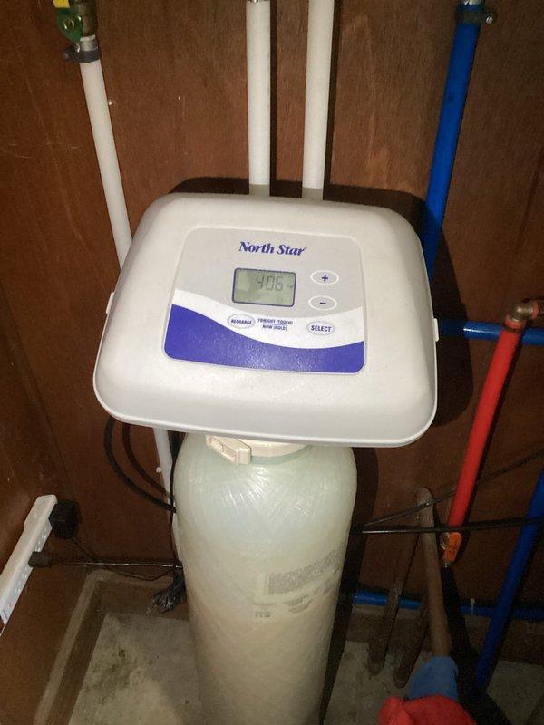 Responded to service call for water leak from bottom of North Star water softener system. Inspected the unit and identified damaged internal distribution valve causing water to leak from base of tank. Replaced faulty valve component and verified proper operation of system with no further leakage observed.