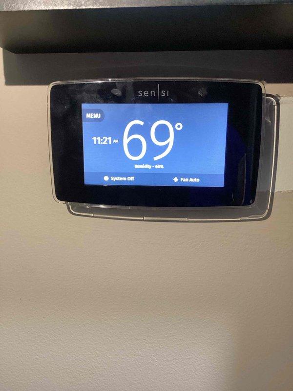 Performed monthly basic heating maintenance service on CCHP system. Inspected Sensi thermostat (displaying 69°F/69% humidity), which was functioning correctly with system off. Visual inspection of Goodman outdoor unit showed proper installation with protective cover in place, though some yard debris was noted around the unit perimeter.