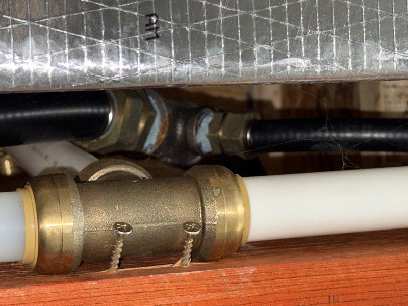 Performed comprehensive inspection of gas system including stove and fireplace insert connections. Located and documented brass fittings and connection points in confined space with visible solder marks. Customer requested removal of gas log fireplace insert with subsequent line capping; provided estimate for complete service including leak detection and proper gas line termination.
