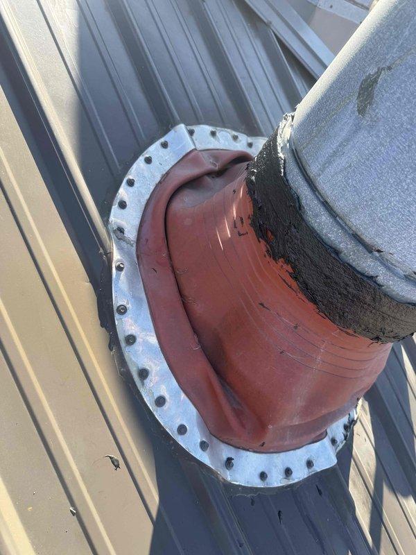 Completed warranty service on HVAC installation by inspecting and resealing roof penetration where vent pipe exits through metal roof. Applied tar sealant at the junction of the pipe and flexible boot to ensure proper weatherproofing. Will return to apply additional tar sealant to completely secure the roof penetration against potential water intrusion.