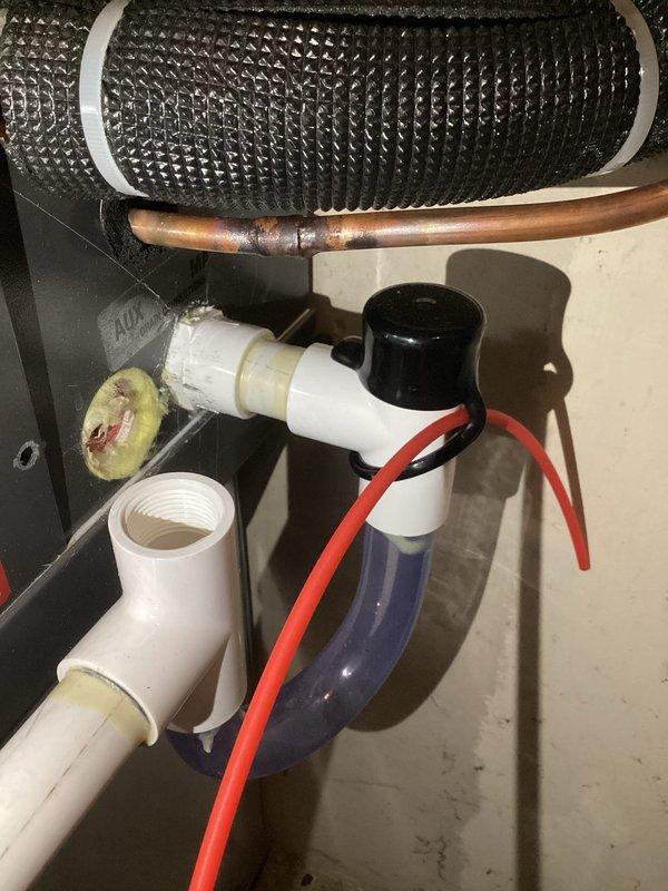 Responded to warranty service call for reported water accumulation near HVAC system. Inspected condensate drain system and identified leak at PVC connection point showing adhesive residue/mineral buildup. System temperature and humidity readings were within normal parameters (70°F/52% humidity) with cooling function operational.