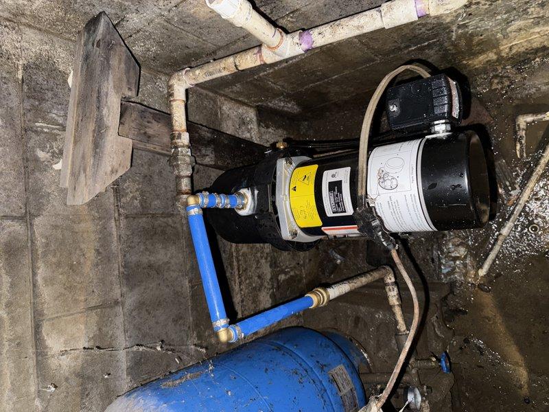 Completed the well pump installation and retrieved sump pumps as scheduled. Installed a new pressure tank with proper PVC connections to the existing water system. The complete installation is operational and properly fitted to the concrete utility area.