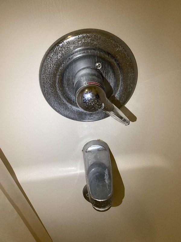 Diagnosed and repaired multiple plumbing issues including continuously running toilets and slow dripping sinks. Inspected shower/tub fixture showing significant mineral buildup on escutcheon plate and handle, as well as drain with visible tarnishing and mineral deposits. Discussed potential kitchen sink replacement options with customer.