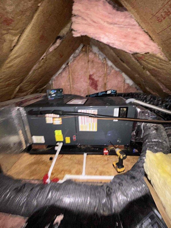 Performed diagnostic assessment of non-functioning heat pump system located in attic space. Inspected internal control board circuitry and connections, noting multiple colored wires (red, black, green, blue, yellow, brown, white) connected to the main circuit board. System was displaying error code and failing to initiate heating cycle; documented condition with photographic evidence of control panel interior and unit installation environment.