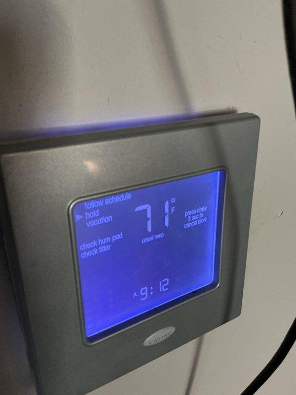 Performed monthly basic heating maintenance service on Carrier system. Inspected thermostat operation, confirming proper functionality with display showing 71°F and system reminders for humidifier pad and filter checks. Examined equipment labels and verified R-410A Puron refrigerant system specifications.