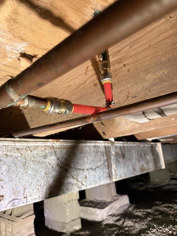 Diagnosed humming noise under bathroom toilet as deteriorated copper supply piping. Located corroded copper elbow fitting showing significant oxidation and patina formation. Replaced damaged section of copper plumbing and installed new shutoff valve to resolve noise issue. Verified proper water flow and absence of leaks after repair.