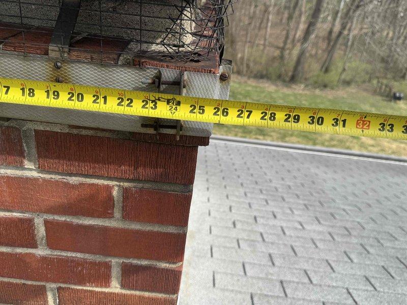 Conducted warranty inspection of flue installation, taking measurements of the brick chimney structure and surrounding roof area. Documented dimensions of approximately 85 inches across the roof section and 17-34 inches at the chimney, verifying proper clearances and installation specifications to address reported flue issues.