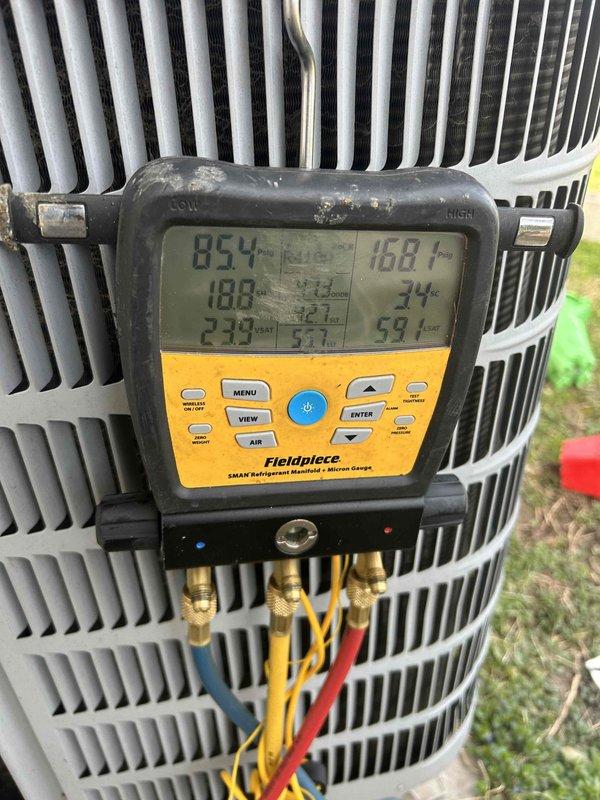 # Service Report: No Cooling - Central Air System

## Summary
Responded to no cooling complaint on 10-15 year old central air conditioning system with reported intermittent heating issues. Performed diagnostic evaluation of outdoor condensing unit and measured refrigerant pressures and temperatures using digital manifold gauges.

## Work Performed

Arrived on-site within scheduled appointment window to address air conditioning system not activating. Customer reported AC not kicking on and previous intermittent heating performance concerns on central air system.

Conducted visual inspection of outdoor condensing unit positioned on concrete pad at side of residence. Unit appeared to be in serviceable condition with standard cylindrical configuration and perimeter metal grille. Accessed service ports on condensing unit to perform refrigerant system diagnostics.

Connected Fieldpiece SMAN digital refrigerant manifold with three-hose setup (standard yellow, blue, and red service hoses) to u