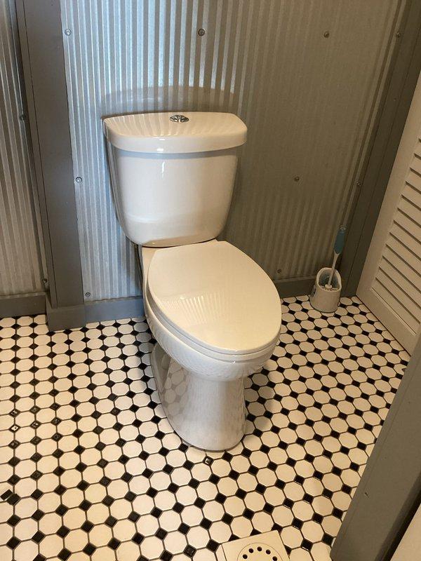 Responded to service call for loose toilet fixture. Upon inspection, found toilet base had become detached from floor mounting. Removed existing wax ring and hardware. Cleaned flange and toilet base thoroughly. Installed new closet bolts and wax ring seal. Repositioned toilet over flange, ensuring proper alignment with drain opening. Secured fixture to floor with new mounting hardware, torquing bolts evenly to prevent cracking porcelain while achieving stable connection. Verified toilet stability and tested flush operation to confirm proper seal and drainage. Unit now securely mounted and fully operational.