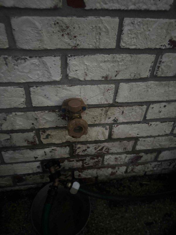 Responded to a main line plumbing concern at a residential property where an aging copper pipe fitting protruding from an interior brick wall showed significant corrosion and oxidation. Inspected the deteriorated T-junction fitting, documented the extent of weathering and patina buildup, and assessed the condition of the connection point to determine necessary repairs for maintaining proper main line function and preventing potential leaks or failures.