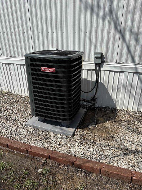 Completed installation of new Goodman heat pump system with matching coil. Unit was mounted on concrete pad with proper gravel base and landscaping border, electrical disconnect installed on dedicated pole for code compliance, and new Honeywell Home digital thermostat programmed and configured for system operation.
