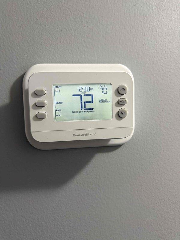 Completed installation of new Goodman heat pump system with matching coil. Unit was mounted on concrete pad with proper gravel base and landscaping border, electrical disconnect installed on dedicated pole for code compliance, and new Honeywell Home digital thermostat programmed and configured for system operation.