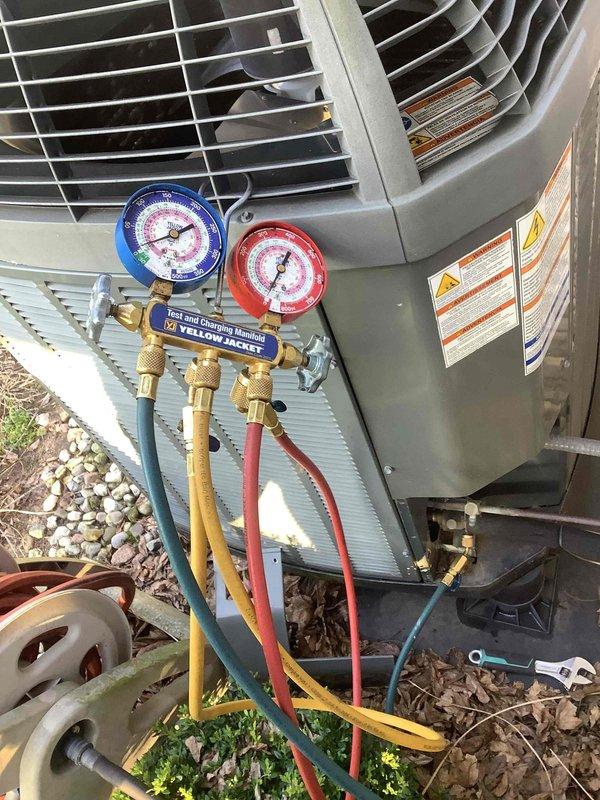 Responded to no cooling complaint on residential air conditioning system. Connected manifold gauge set to condenser unit to perform diagnostic pressure testing and evaluate refrigerant charge levels. Documented unit specifications and manufacturer data plate information for service records.