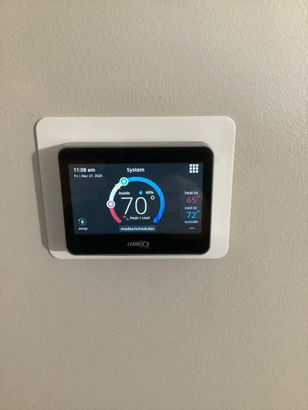 Returned to property to complete thermostat replacement, successfully installing new Lennox M30 smart thermostat. Unit was mounted, programmed with heating and cooling setpoints, and verified operational with touchscreen display showing proper temperature readings and system status.