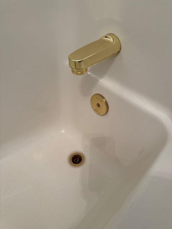 Responded to main level guest bathroom for non-functioning bathtub drain stopper. Upon inspection, confirmed existing brass-finished trip lever drain assembly was failing to hold water, allowing continuous drainage. Provided estimate for replacement of complete bathtub drain and overflow assembly with matching brass finish to coordinate with existing tub spout and fixtures.