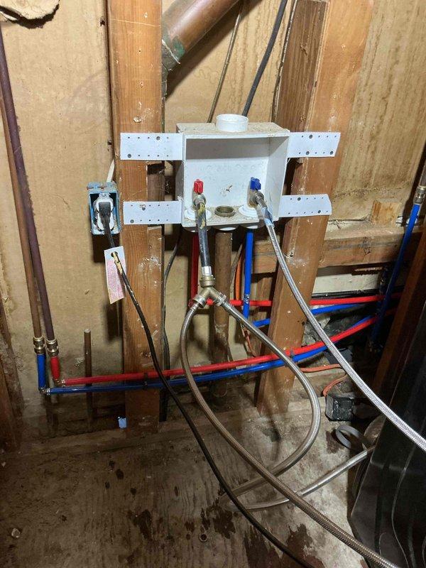 Completed comprehensive water service repipe for residential property, replacing outdated plumbing infrastructure with modern PEX piping system. Interior installation included mounting washing machine outlet box with hot and cold water valves, installing brass manifold assembly, and routing color-coded PEX lines (red for hot, blue for cold) throughout the wall cavity with proper support strapping and connections using braided stainless steel supply lines. Exterior work involved installing new hose bib on brick wall foundation to provide outdoor water access. All connections were secured, tested for leaks, and verified for proper water flow and pressure throughout the system.