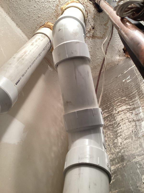 Responded to warranty call for leaking vent line with visible water damage on floor. Upon inspection, identified leak at PVC pipe joint connection in the condensate drain system. Disassembled affected joint, cleaned and prepped surfaces, and reassembled connection with proper primer and cement application to ensure watertight seal. Verified all adjacent PVC connections for integrity and proper support. Tested system operation and confirmed no further leakage present. Documented installation with photos showing pipe routing, connections, and surrounding HVAC components including refrigerant lines and drainage system.