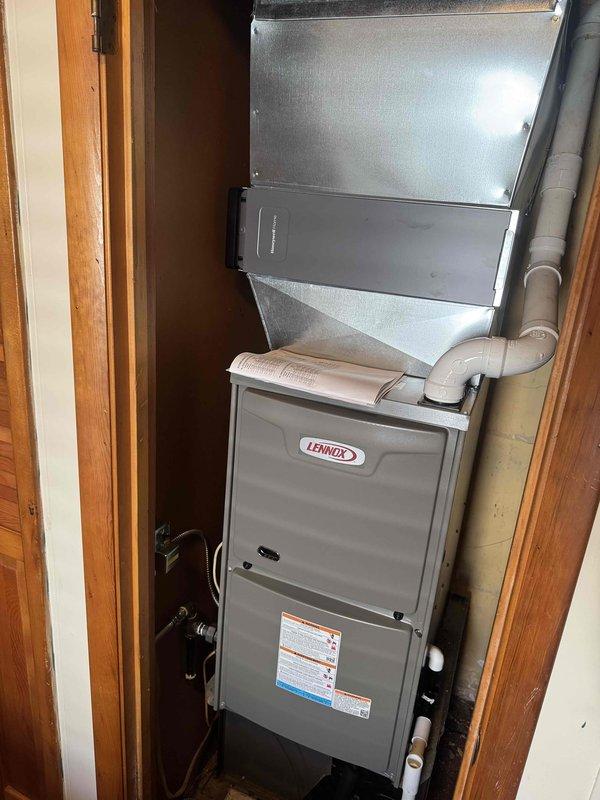 Successfully installed Lennox 80-90% AFUE gas furnace in residential utility closet with complete ductwork connections and PVC venting system. Post-installation testing confirmed proper airflow and system operation with supply register temperature reading of 43.3°F, indicating unit cycling and operational readiness.