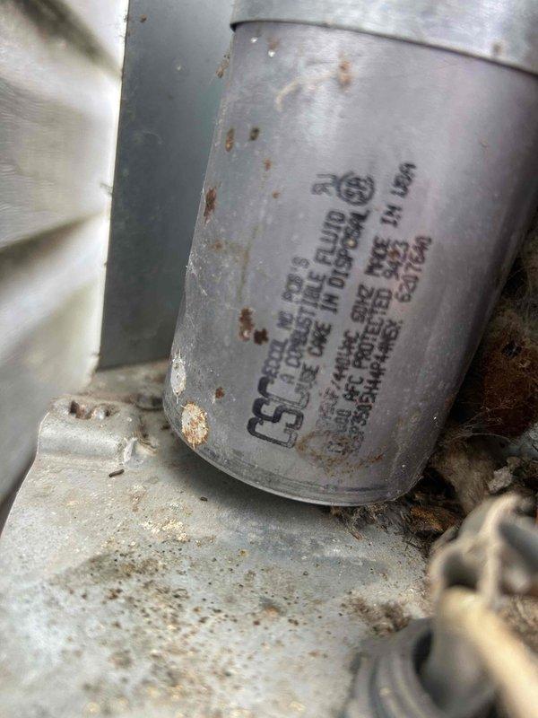 Responded to no cooling complaint on residential split system air conditioning unit. Upon arrival, confirmed indoor unit was operational but outdoor condensing unit was not running. Diagnosed failed capacitor on outdoor unit, evidenced by visible corrosion and rust on capacitor casing. Replaced defective capacitor, restored power to system, and verified proper operation of outdoor condensing unit with normal compressor and fan function.