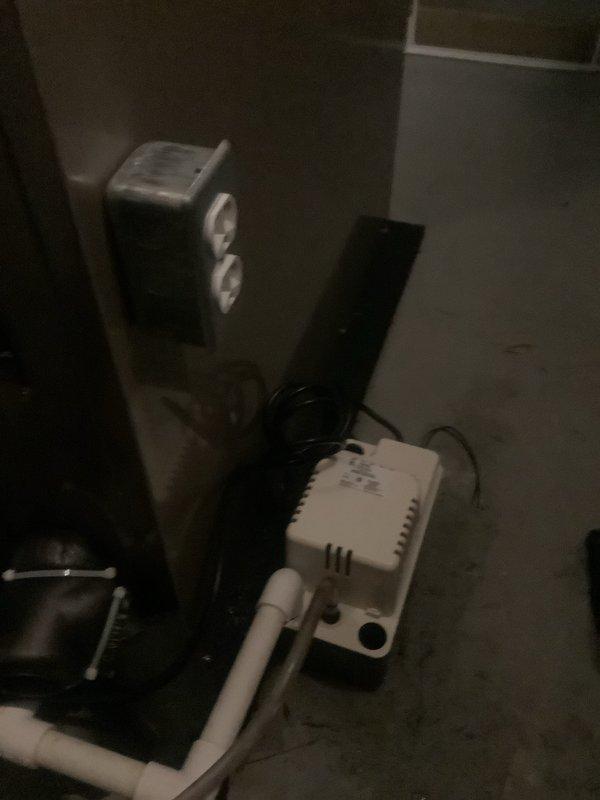 Completed HVAC system installation with all components properly positioned and connected in mechanical room. Installed air handler unit, condensate pump assembly, and associated refrigerant lines with proper insulation. Connected PVC condensate drain lines, copper refrigerant piping, and flexible gas line to manufacturer specifications, ensuring all connections are secure and system is ready for operation under warranty coverage.