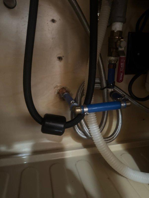 Responded to callback regarding sink issue that developed following previous leak repair. Upon inspection of under-sink plumbing connections, verified all water supply lines, braided flex lines, shut-off valves, and drain connections for proper installation and function. Documented existing plumbing configuration including dishwasher connections, hot and cold water supply valves with blue and brass fittings, and drainage system. All connections were secure with no active leaks detected at time of inspection.