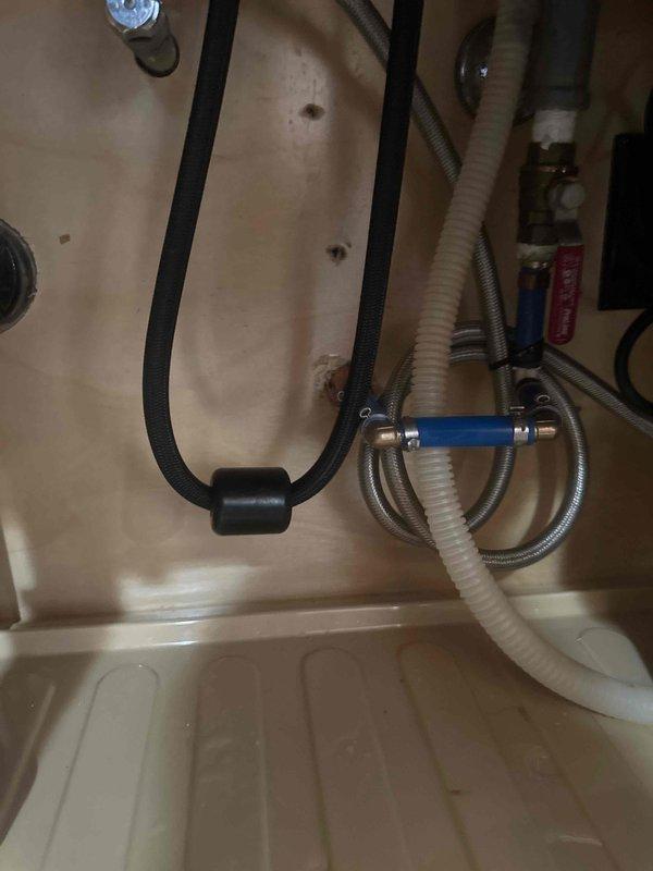 Responded to callback regarding sink issue that developed following previous leak repair. Upon inspection of under-sink plumbing connections, verified all water supply lines, braided flex lines, shut-off valves, and drain connections for proper installation and function. Documented existing plumbing configuration including dishwasher connections, hot and cold water supply valves with blue and brass fittings, and drainage system. All connections were secure with no active leaks detected at time of inspection.