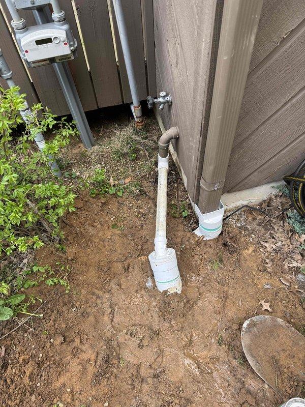 Excavated and installed new drainage piping system for sump pump discharge and downspout routing in residential backyard. Trenched pathway through lawn area to accommodate underground PVC drainage lines, ensuring proper grade and slope for water flow away from foundation. Installed PVC piping configuration with trap assembly along building exterior, connecting sump pump outlet and downspout drainage to new underground system. Completed plumbing maintenance inspection of existing utility connections and verified proper operation of all drainage components.