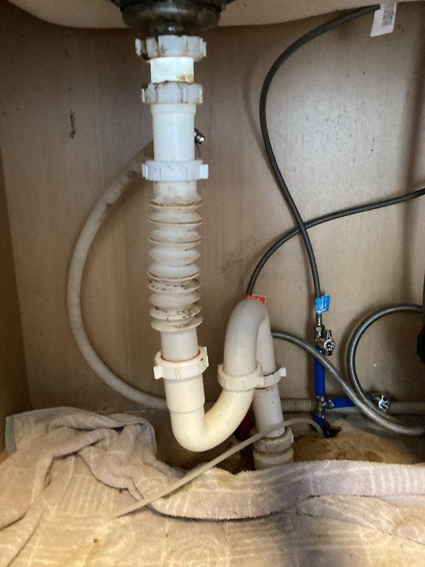 Returned to address issues from recent waterline replacement work. Reconnected kitchen sink drain assembly that had been left disconnected during previous installation, which was causing water to discharge directly onto the floor. Repaired leaking connection at downstairs bathroom where new waterline from basement penetrated through to fixture. Verified all connections were secure and tested system for proper drainage and water supply operation with no further leaks detected.