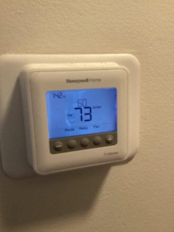 # HVAC Service Call - No Cooling Issue

Responded to no cooling complaint on residential air conditioning system over 10 years old. Upon arrival, verified Honeywell Home Pro Series thermostat was calling for cooling with display reading 73°F. Proceeded to outdoor unit located on concrete pad against house exterior. Found cylindrical condenser unit with black mesh protective grille heavily surrounded by yard debris, dead plant material, pine needles, and twigs accumulated around base and blocking airflow at ground level.

Cleared all debris from around unit perimeter and removed organic material restricting air intake. Inspected electrical disconnect and conduit connections - found secure with no visible damage. Cleaned condenser coil fins of dirt and vegetation buildup to restore proper heat exchange. Verified unit startup, checked amperage draw on compressor and fan motor - readings within manufacturer specifications. System now cooling properly with adequate airflow restored. Recomme