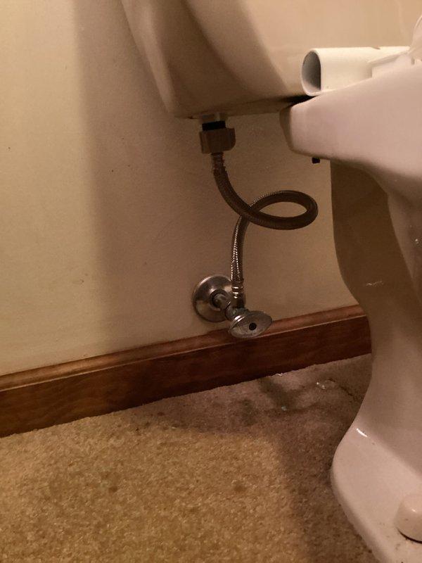 Responded to water leak at refrigerator supply line connection point. Upon arrival, flooring contractors had relocated refrigerator from wall, exposing active leak at wall-mounted water supply valve where line connects to appliance. Accessed plumbing through existing wall opening to assess shut-off valve and supply line configuration. Shut off water supply at chrome-plated angle stop valve to stop active leak. Inspected braided stainless steel supply line connection and compression fitting at wall outlet for damage or improper seating. Tightened compression connection and verified proper seal at valve outlet. Tested system by restoring water supply and checking for leaks at connection point under pressure. Confirmed repair successful with no visible water discharge. Advised regarding proper clearance requirements when relocating appliance in future to prevent strain on supply line connections.