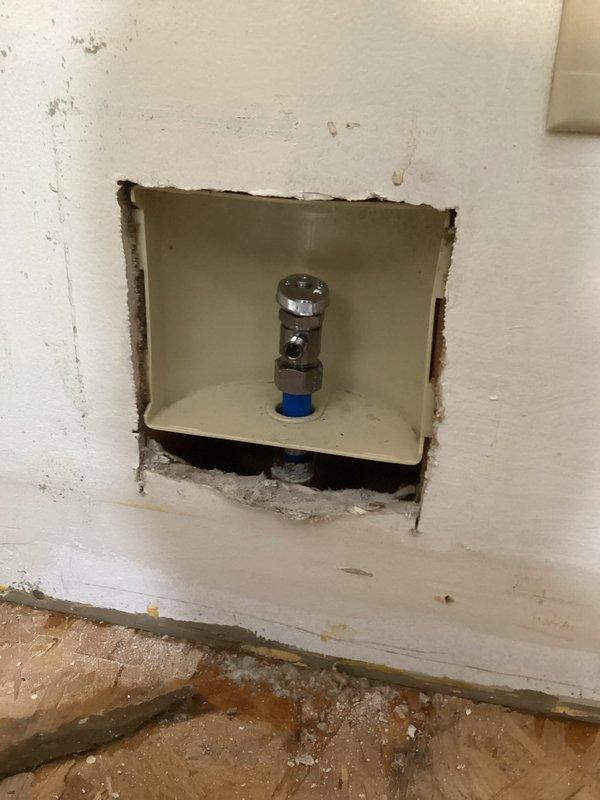 Responded to water leak at refrigerator supply line connection point. Upon arrival, flooring contractors had relocated refrigerator from wall, exposing active leak at wall-mounted water supply valve where line connects to appliance. Accessed plumbing through existing wall opening to assess shut-off valve and supply line configuration. Shut off water supply at chrome-plated angle stop valve to stop active leak. Inspected braided stainless steel supply line connection and compression fitting at wall outlet for damage or improper seating. Tightened compression connection and verified proper seal at valve outlet. Tested system by restoring water supply and checking for leaks at connection point under pressure. Confirmed repair successful with no visible water discharge. Advised regarding proper clearance requirements when relocating appliance in future to prevent strain on supply line connections.