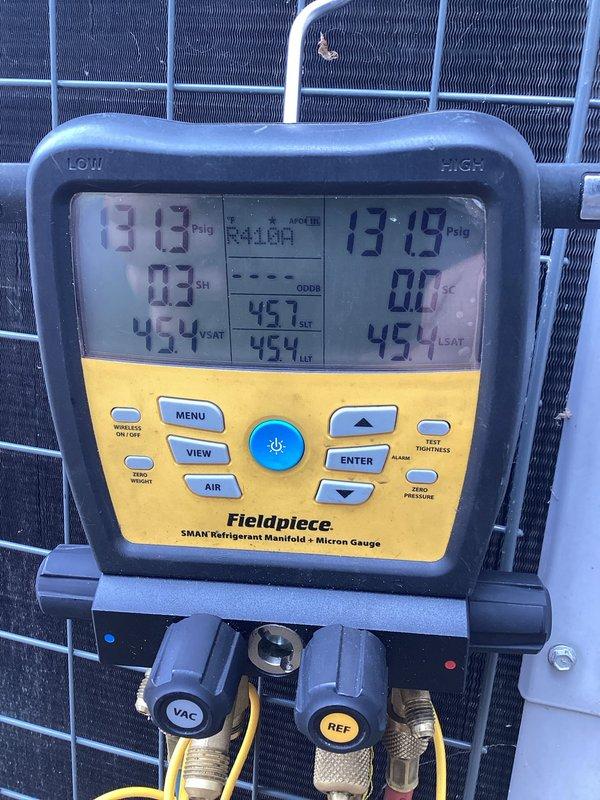 Responded to service call to verify refrigerant charge levels on residential air conditioning system. Connected Fieldpiece SMAN digital manifold gauges to measure system pressures and confirmed R-410A refrigerant operating at 13.9 psig suction pressure and 137.9 psig discharge pressure with saturation temperature of 45.4°F. System refrigerant charge verified to be within manufacturer specifications with no adjustments required.