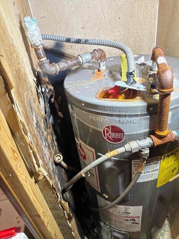 Responded to service call for water leak affecting the water heater and under-sink plumbing. Upon inspection, identified active leaking from corroded copper piping at the top of the Rheem Performance water heater, with additional leak present at the under-sink connection. The copper pipes exhibited significant oxidation, rust-colored patina, and corrosion throughout the vertical sections and connection points, indicating advanced deterioration of the plumbing system. Documented existing conditions with photographs showing the extent of corrosion on all copper connections, the water heater installation, and surrounding plumbing infrastructure. Provided assessment of the compromised piping and recommended necessary repairs to address the active leaks and prevent further water damage to the water heater and surrounding area.