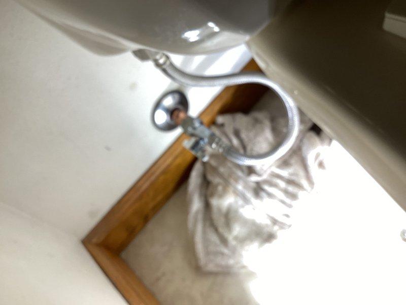 Returned to address additional toilet repairs identified during previous service call where obsolete metal supply lines were replaced. Coordinated entry access with flooring contractors on site. Inspected bathroom fixtures and documented conditions including toilet installation with recently installed braided stainless steel supply line and shutoff valve. Observed secondary bathroom shower stall exhibiting severe deterioration of drain assembly with extensive rust corrosion on metal components and water damage to surrounding composite flooring and wooden trim. Completed photographic documentation of fixture conditions for service records.