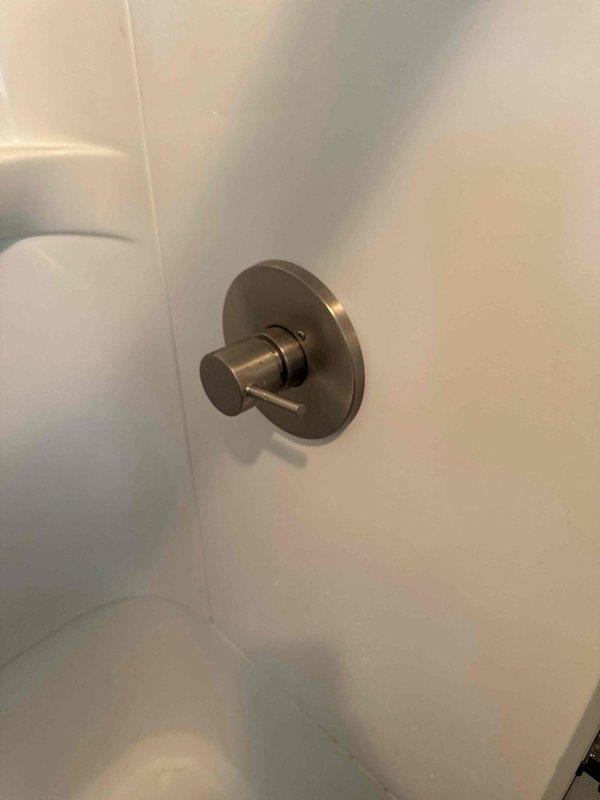 Responded to callback for shower valve installed previous day with no hot water delivery. Inspected newly installed shower control valve and trim on white tiled shower wall. Verified proper installation of brushed nickel single-lever thermostatic valve assembly. Adjusted cartridge positioning to restore proper hot water function and confirmed temperature control operation working correctly.