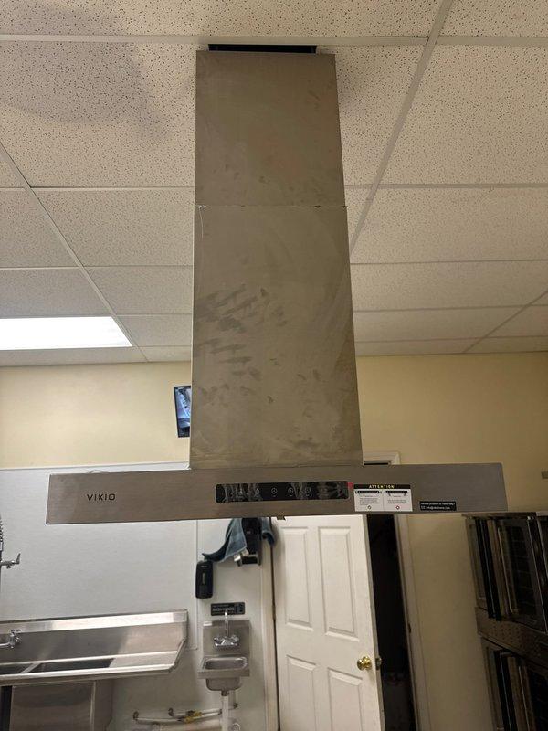 Responded to service call regarding malfunctioning kitchen exhaust fan system producing abnormal noise. Upon arrival, inspected VIKIO brand stainless steel chimney-style range hood previously installed in 2024. Conducted diagnostic assessment of ventilation unit, control panel, and ductwork extending through ceiling. Documented current condition of exhaust system and surrounding kitchen appliances with photographic evidence for warranty verification purposes.