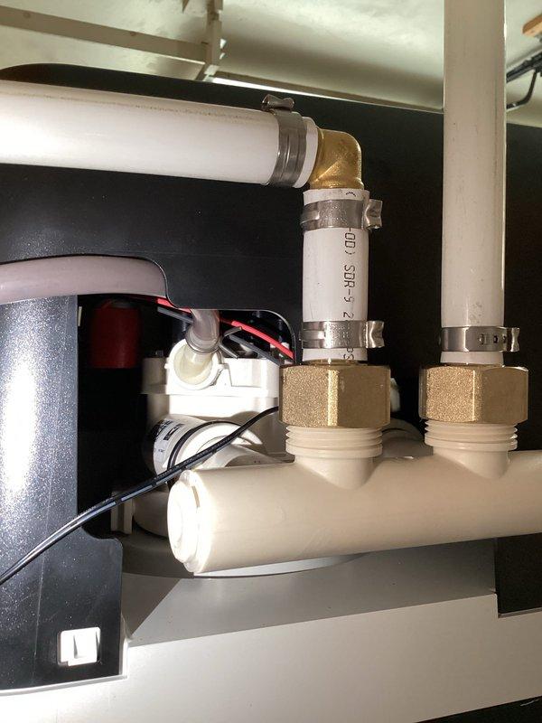 Completed installation of residential water softener system. Installed new water softener tank with control valve assembly and brine tank in exterior location. Connected unit to existing water supply line using PVC piping, brass compression fittings, and appropriate shut-off valves. Configured under-sink plumbing connections with T-junction distribution system to integrate softener bypass. Installed electrical components for automatic regeneration cycle control. Secured all connections with metal hose clamps and tested system for proper operation and leak-free performance. Unit is fully operational and programmed for optimal water conditioning.