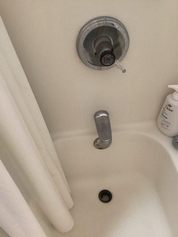 Completed monthly prepaid plumbing inspection of residential property. Identified and documented minor leaks at bathroom tub spout and water softener connections in basement utility area. Inspected bathroom fixtures including chrome shower control valve, tub spout, and drain assembly, noting proper operation of temperature control mechanism. Examined Culligan water softening system with dual tank configuration, checking control head unit functionality and connection integrity at inlet/outlet points with blue handle valve. Photographed areas of concern for maintenance records, including visible water staining on basement concrete floor near water treatment equipment. All fixtures and plumbing components documented for ongoing maintenance tracking.