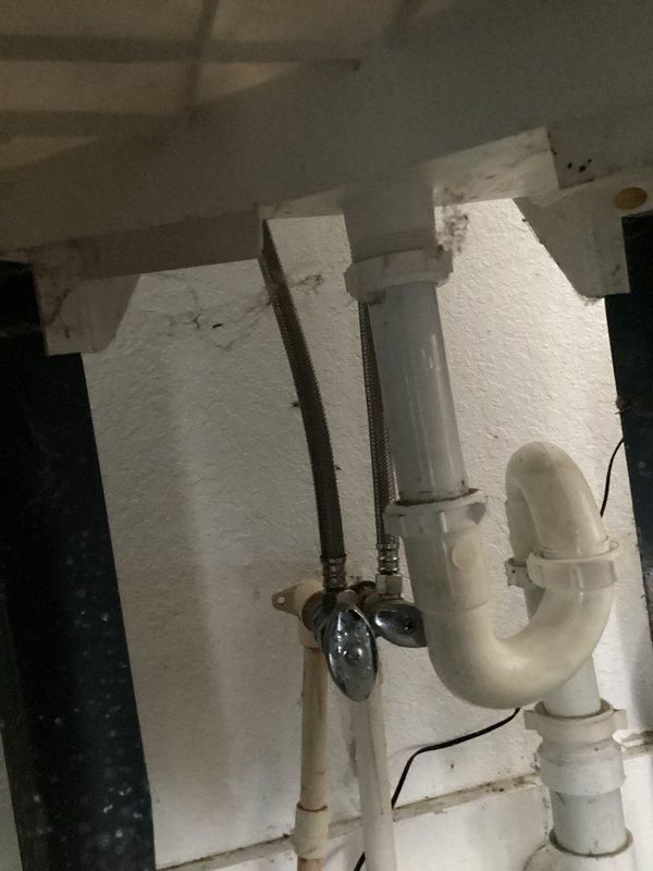 Replaced defective supply stop valve and installed new lavatory faucet assembly with chrome-finished flexible supply lines. Repaired lavatory drain connections and installed new white P-trap assembly to ensure proper drainage and prevent future leaks.