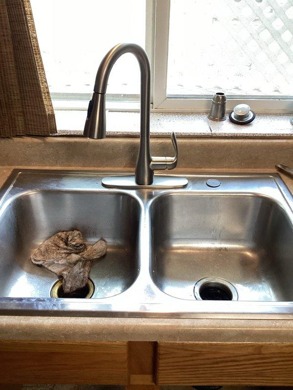 Installed new chrome dual-handle faucet on bathroom vanity with beige marble countertop. Addressed drainage issue in bathroom sink to restore proper water flow and prevent future stoppages.