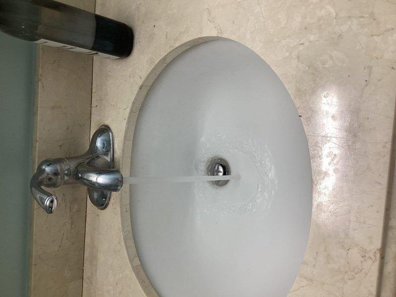 Installed new chrome dual-handle faucet on bathroom vanity with beige marble countertop. Addressed drainage issue in bathroom sink to restore proper water flow and prevent future stoppages.