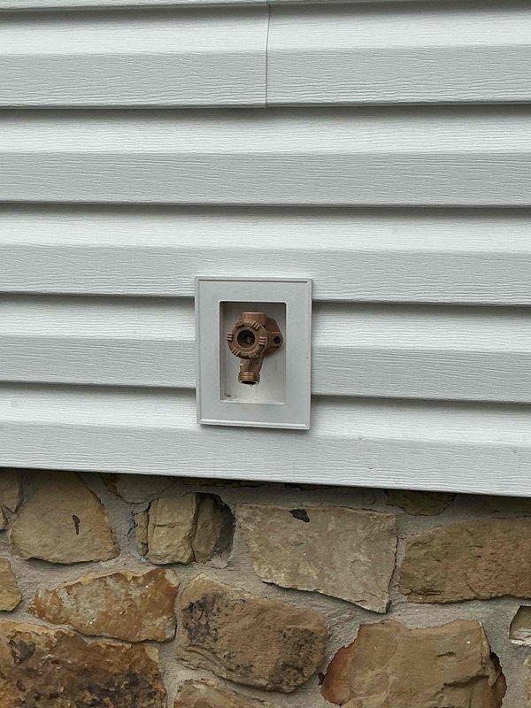 Returned to property for callback on exterior hose bib that was replaced earlier in the day. Upon arrival, inspected the copper spigot mounted in white access panel on vinyl siding exterior wall. Identified leak at connection point and corrected installation issue. Verified proper function of hose bib, confirmed no leaks present, and tested water flow. Unit operating correctly at time of departure.