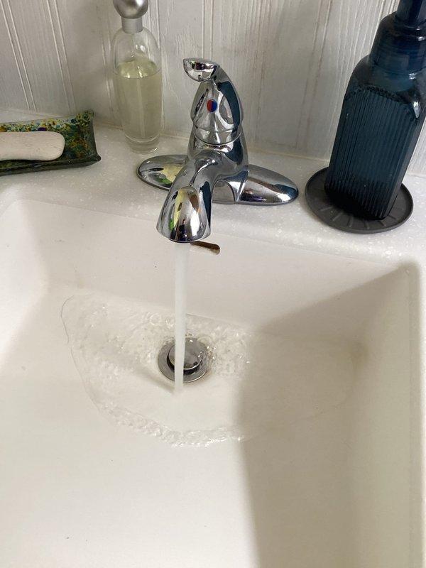 Completed monthly plumbing membership inspection of residential bathroom and water heater systems. Verified proper operation of chrome two-handle faucet with adequate water flow and drainage, inspected sink basin and drain assembly for leaks or damage, and examined water heater installation including pressure relief valve, flexible supply lines, and drainage components. All fixtures found to be functioning properly with no immediate concerns identified, and photographic documentation captured for service records.