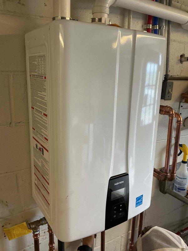 # Tankless Water Heater Installation

Successfully installed a new Energy Star certified tankless water heater unit in basement utility area. Mounted unit securely to concrete block wall and established all necessary water supply connections using copper piping for both hot and cold water lines. Installed isolation valves with color-coded handles (red for hot, blue for cold) at the unit connections to facilitate future maintenance and servicing. 

Configured PVC venting system with proper elbow joints and termination fittings to ensure safe exhaust of combustion gases. Routed vent piping along ceiling and wall with appropriate support brackets to meet manufacturer specifications and local code requirements. Integrated existing copper supply lines with new installation, securing all piping runs with mounting brackets for stability and professional appearance.

Programmed digital control panel and verified proper operation of the unit. Confirmed all connections are leak-free and system i