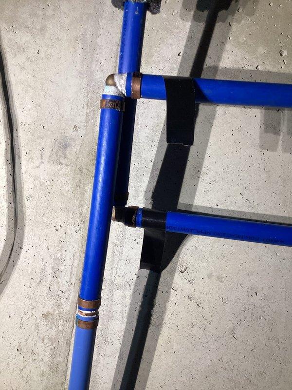 Responded to service call for slow water leaks in residential plumbing system. Upon arrival, conducted thorough inspection of basement utility area and identified active leakage in main water supply lines. Inspected blue PVC vertical drain line with metal mounting bracket and gray pump control junction box, noting moisture accumulation and mineral deposits on concrete floor indicating chronic seepage. Examined flexible supply tubes and connections for signs of deterioration or loose fittings. Assessed black filter component and associated plumbing fixtures for proper operation and seal integrity. Documented existing conditions with photographic evidence showing efflorescence patterns on concrete surface and debris accumulation consistent with ongoing moisture infiltration. Provided diagnosis of leak sources and recommended corrective actions to address water intrusion issues and prevent further damage to basement area.