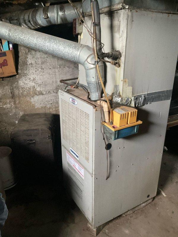 Completed comprehensive estimate for full HVAC system replacement including aging outdoor condenser unit with weathered protective cage and deteriorating basement furnace with corroded copper piping. Documented existing equipment condition through detailed photography, noting significant wear on exterior condenser components and oxidation on furnace connections, and presented available replacement options with current promotional offers including extended labor warranty coverage.