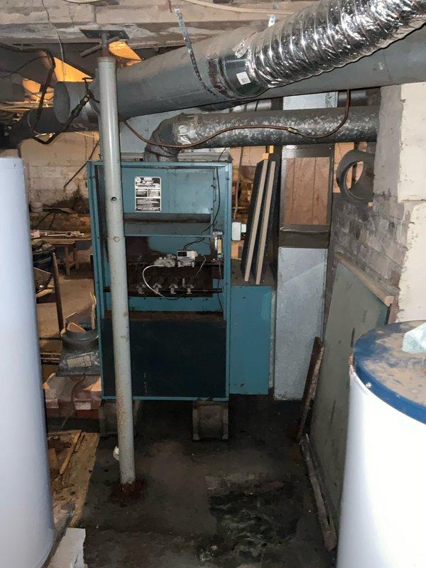 Completed comprehensive assessment of existing residential HVAC system located in unfinished basement for full system replacement estimate. Evaluated aging furnace unit showing visible wear and surface deterioration, along with existing ductwork configuration including horizontal trunk lines and flexible ducting. Documented current equipment condition, basement installation environment with concrete block walls and exposed floor joists, and noted moisture staining on concrete floor near equipment base. Provided customer with complete replacement options and financing alternatives for new HVAC system installation.