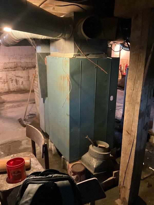 Completed comprehensive assessment of existing residential HVAC system located in unfinished basement for full system replacement estimate. Evaluated aging furnace unit showing visible wear and surface deterioration, along with existing ductwork configuration including horizontal trunk lines and flexible ducting. Documented current equipment condition, basement installation environment with concrete block walls and exposed floor joists, and noted moisture staining on concrete floor near equipment base. Provided customer with complete replacement options and financing alternatives for new HVAC system installation.